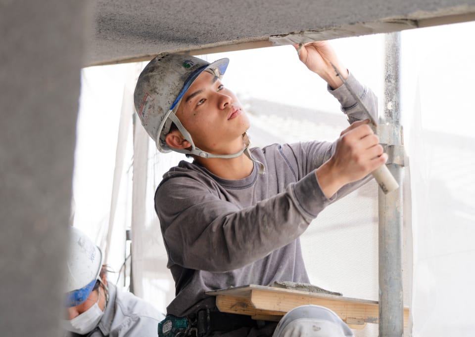 屋根の縁を塗る左官職人3年目の川村さん